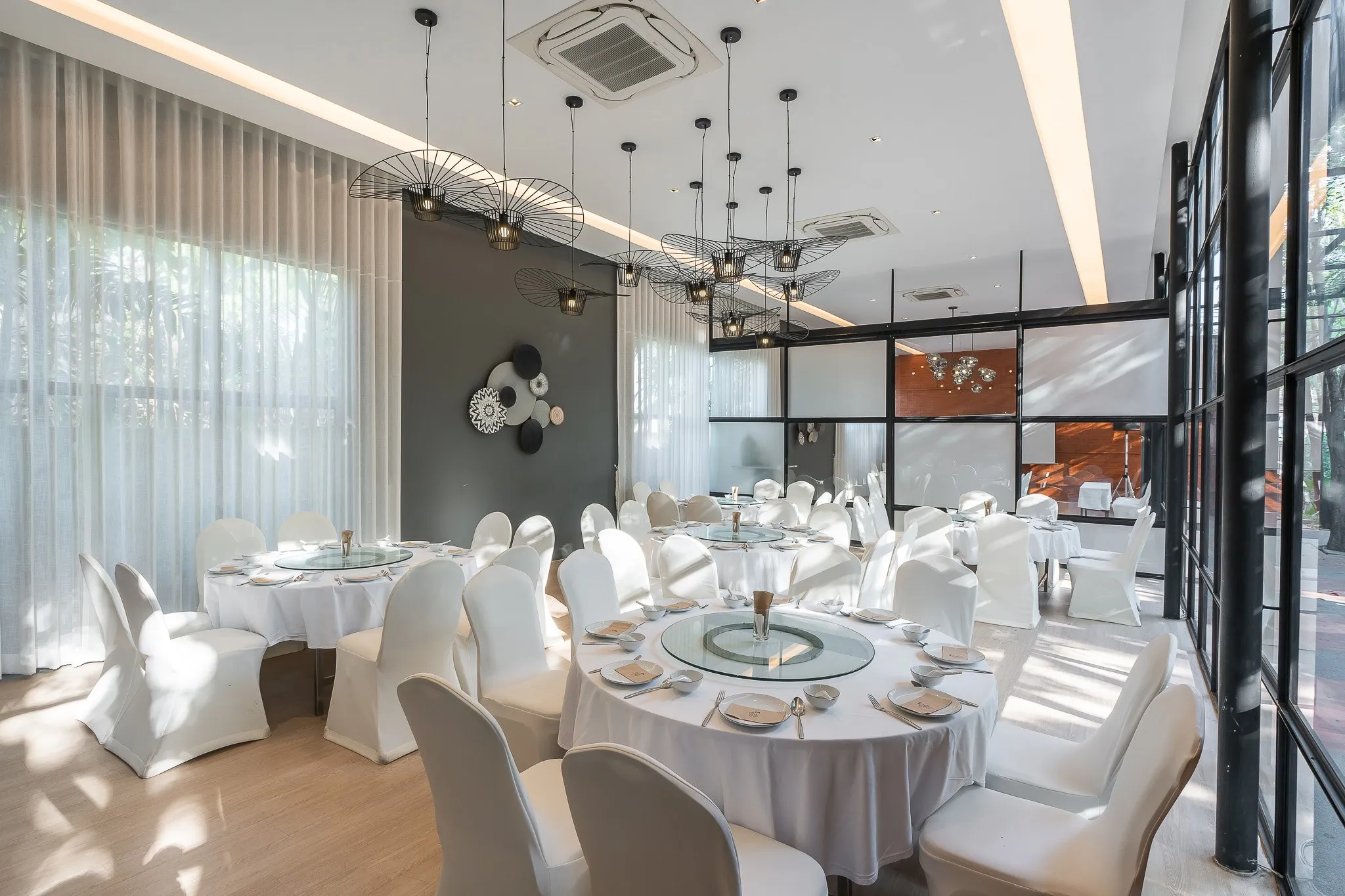 Banquet room with round tables and glass walls onto the garden